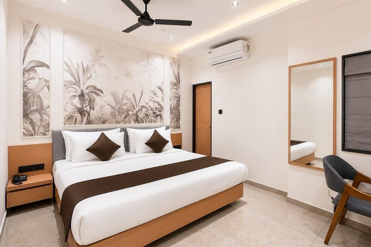 Una habitación de hotel moderna con una cama, un escritorio, una silla, un ventilador de techo y un espejo grande.