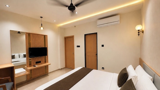 Habitación de hotel con cama, escritorio, televisor, ventilador de techo y aire acondicionado.