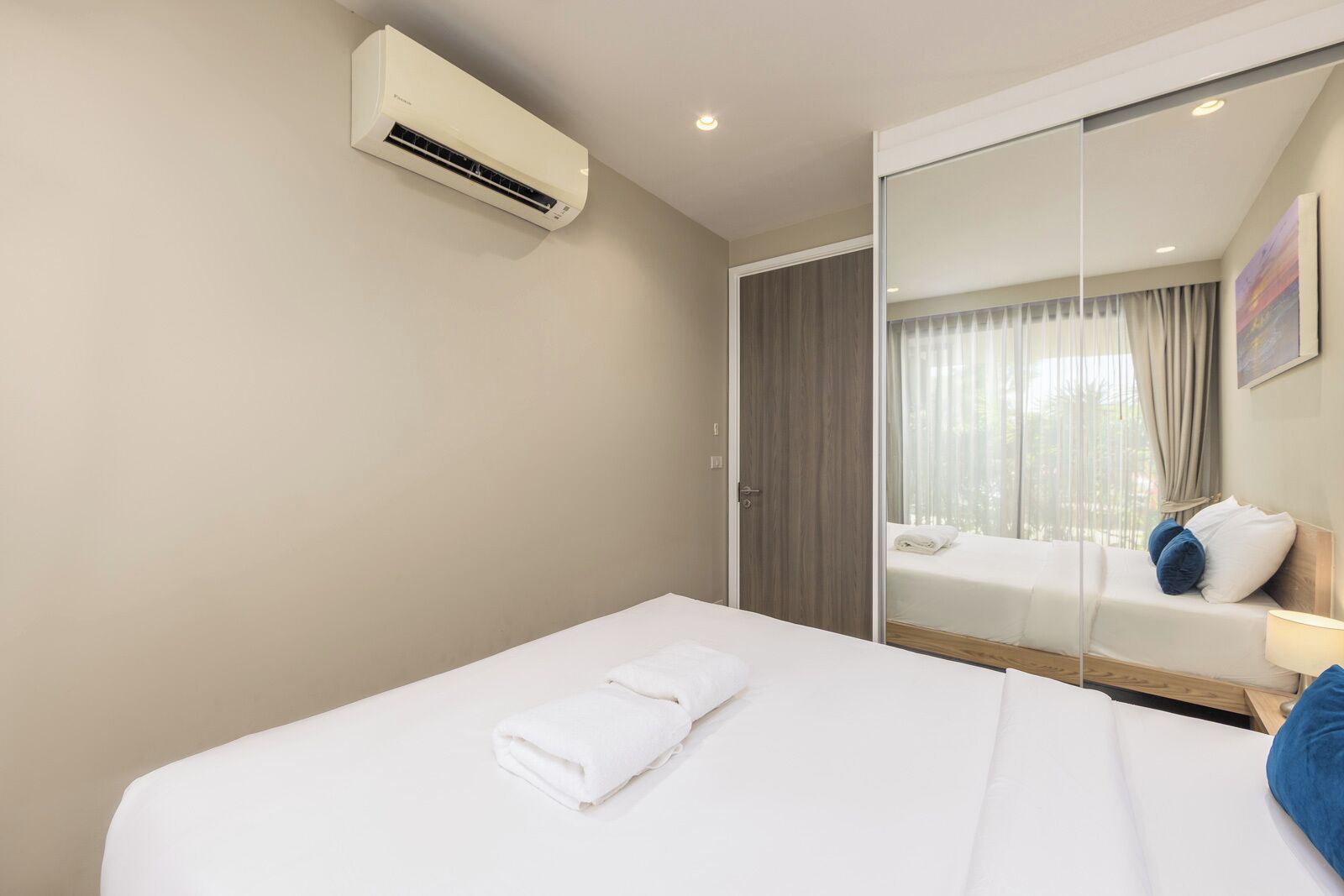 A hotel room with a bed, a large mirror, and an air conditioning unit.