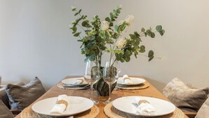 A dining table set with plates, cutlery, and two glass vases with greenery and white flowers. - Diamond Resort BangTao by Tropiclook (Tambon Choeng Thale)