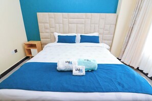 Ein Hotelzimmer mit einem großen Bett, einem Nachttisch aus Holz und einer blauen und weißen Farbgestaltung.