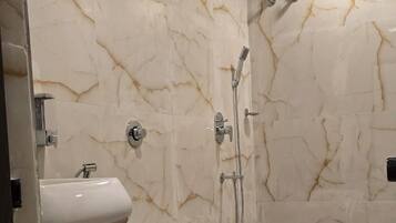 A bathroom with a marble wall, a toilet, a sink, and a shower area.