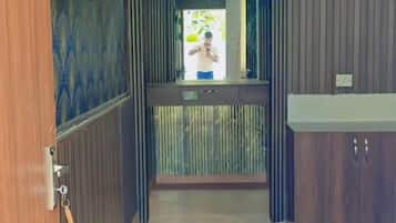 Corredor com porta de madeira, espelho e vista para uma varanda com grades.