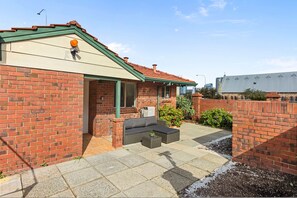 A brick house with a green roof, a patio with outdoor furniture, and a garden area. - Dashing Dome - A Sepal Stay (Perth)