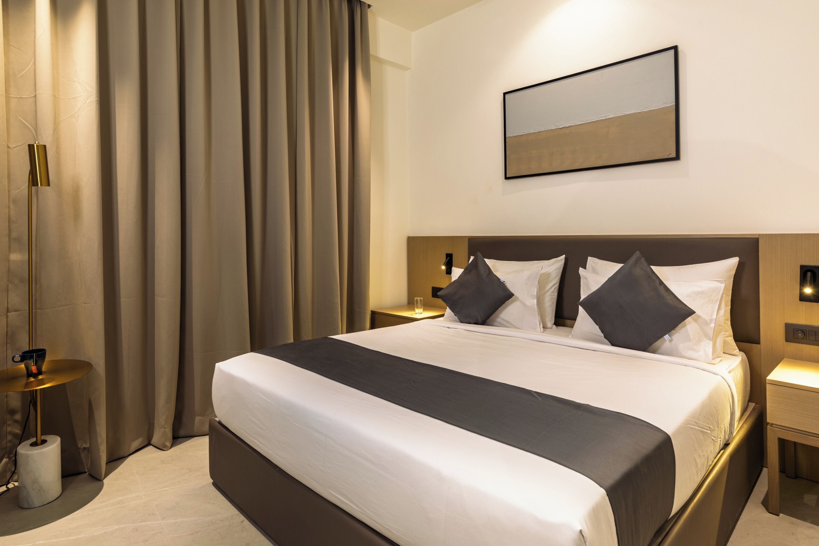 Habitación de hotel con una cama grande, una mesita de noche, una lámpara y un cuadro en la pared.