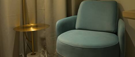 A room with a blue armchair, a floor lamp, and a curtain.