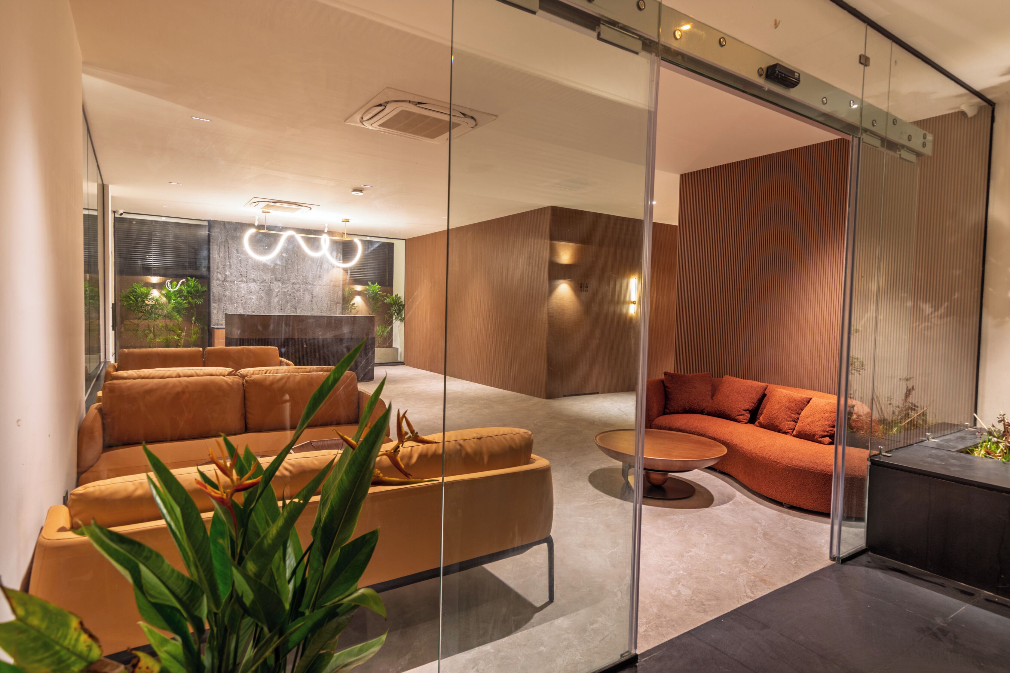 A modern living room with a glass partition, a sofa, a coffee table, and a fireplace.