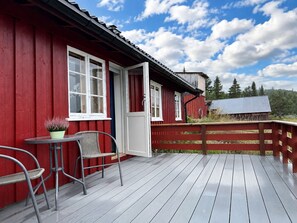 Un edificio di legno rosso con un balcone, un tavolo e due sedie.