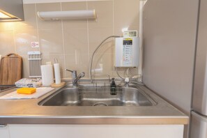 Een keuken met een roestvrijstalen spoelbak, een keukenpapierdispenser en een zeepdispenser.