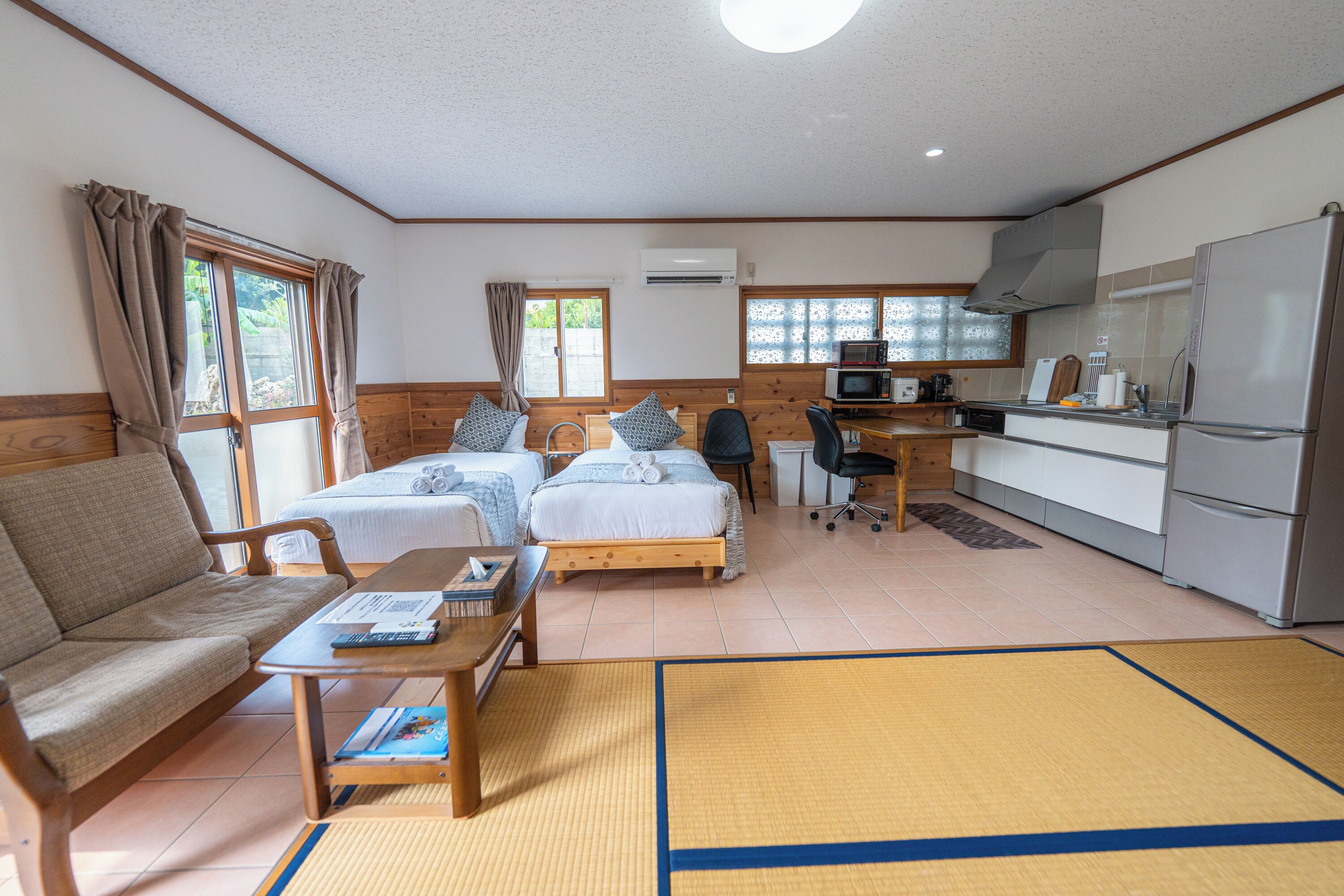 Une chambre d’hôtel compacte comprenant deux lits, un canapé, un petit coin cuisine et une table à manger.