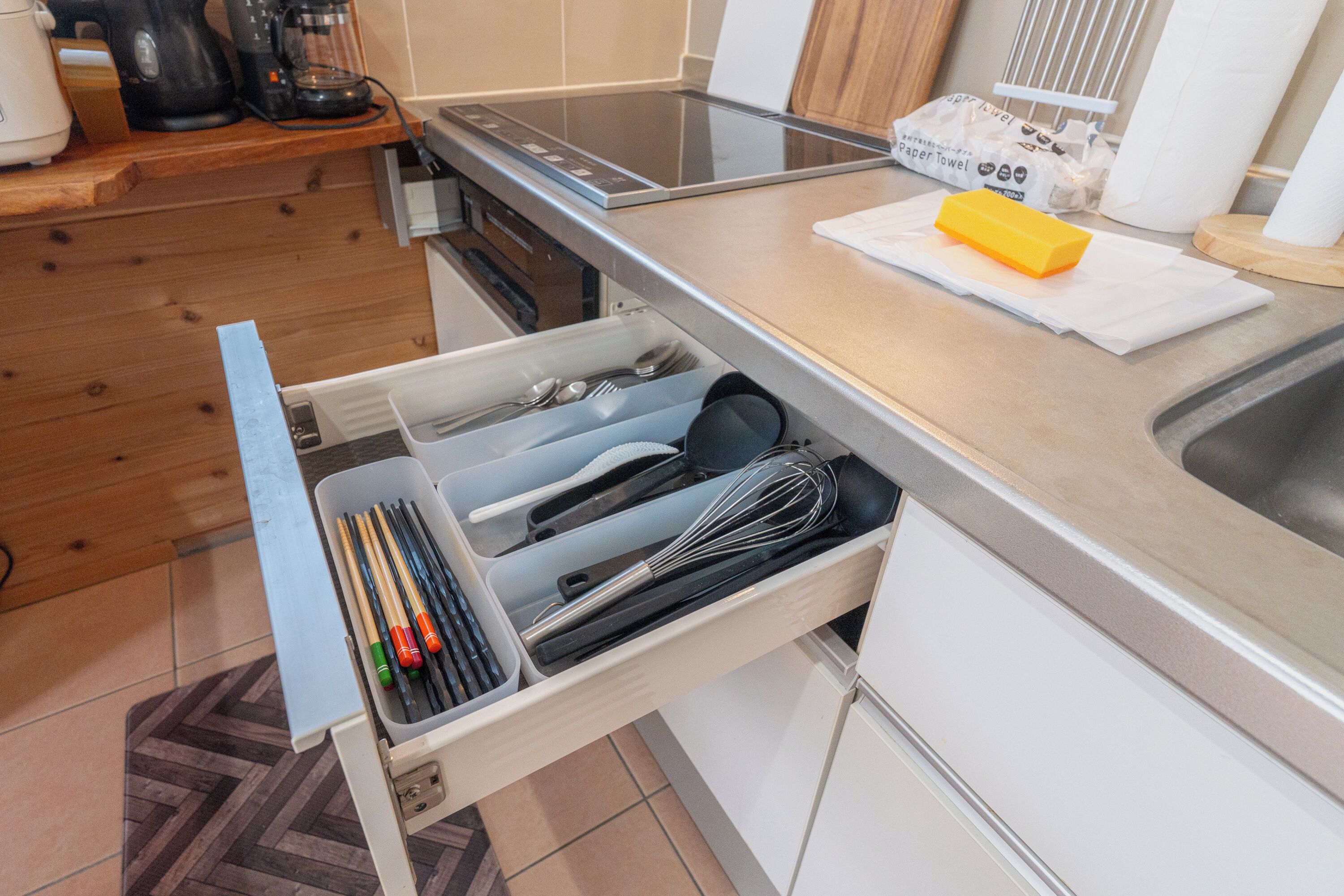 A kitchen with a built-in dishwasher, a coffee maker, and a paper towel dispenser on the countertop.