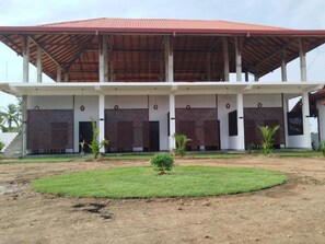 A building with a covered outdoor area, a lawn, and a small garden. - Salt & sand resort (Arugam Bay)
