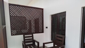 Una habitación con una mesa de madera y dos sillas, un biombo decorativo y una puerta con paneles de vidrio.