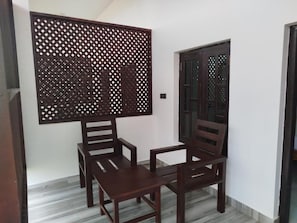 A room with a wooden table and two chairs, a decorative screen, and a door with glass panels. - Salt & sand resort (Arugam Bay)