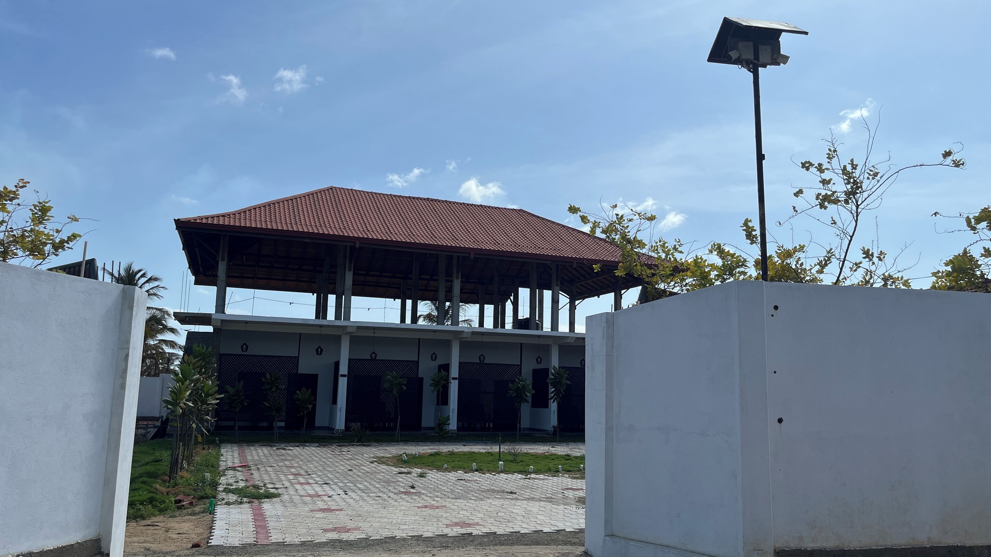 A building with a covered patio area, a paved entrance, and a security camera.