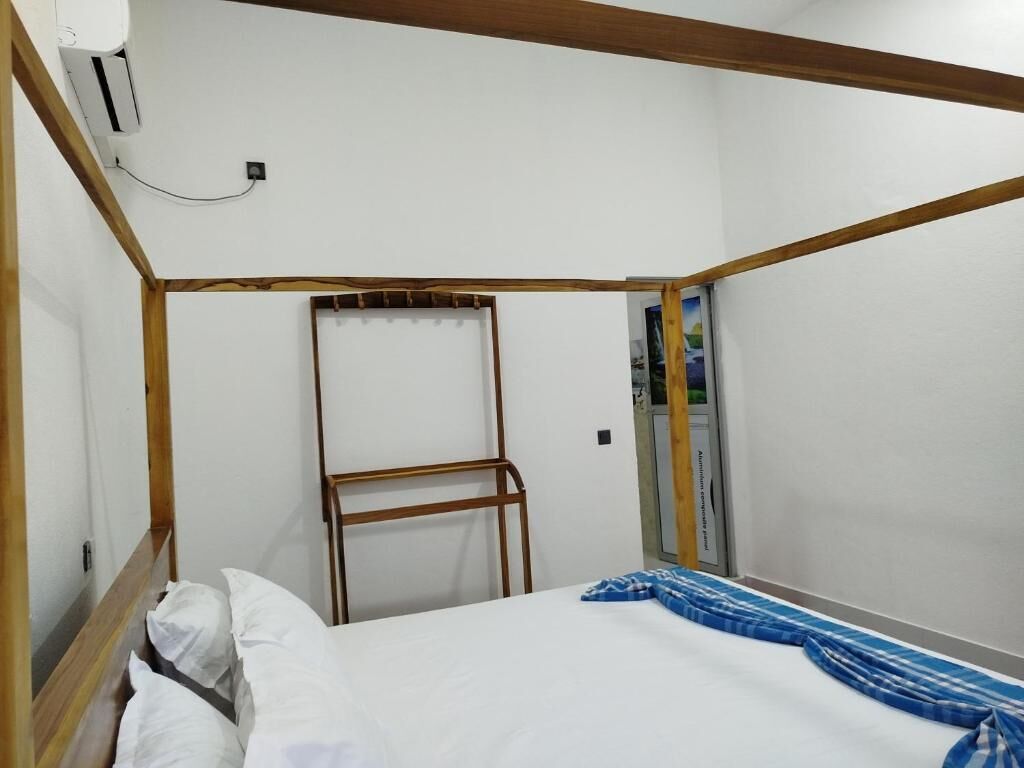 A single bed with white bedding, a wooden headboard, and a blue and white striped blanket.