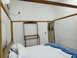 A single bed with white bedding, a wooden headboard, and a blue and white striped blanket. - Salt & sand resort (Arugam Bay)