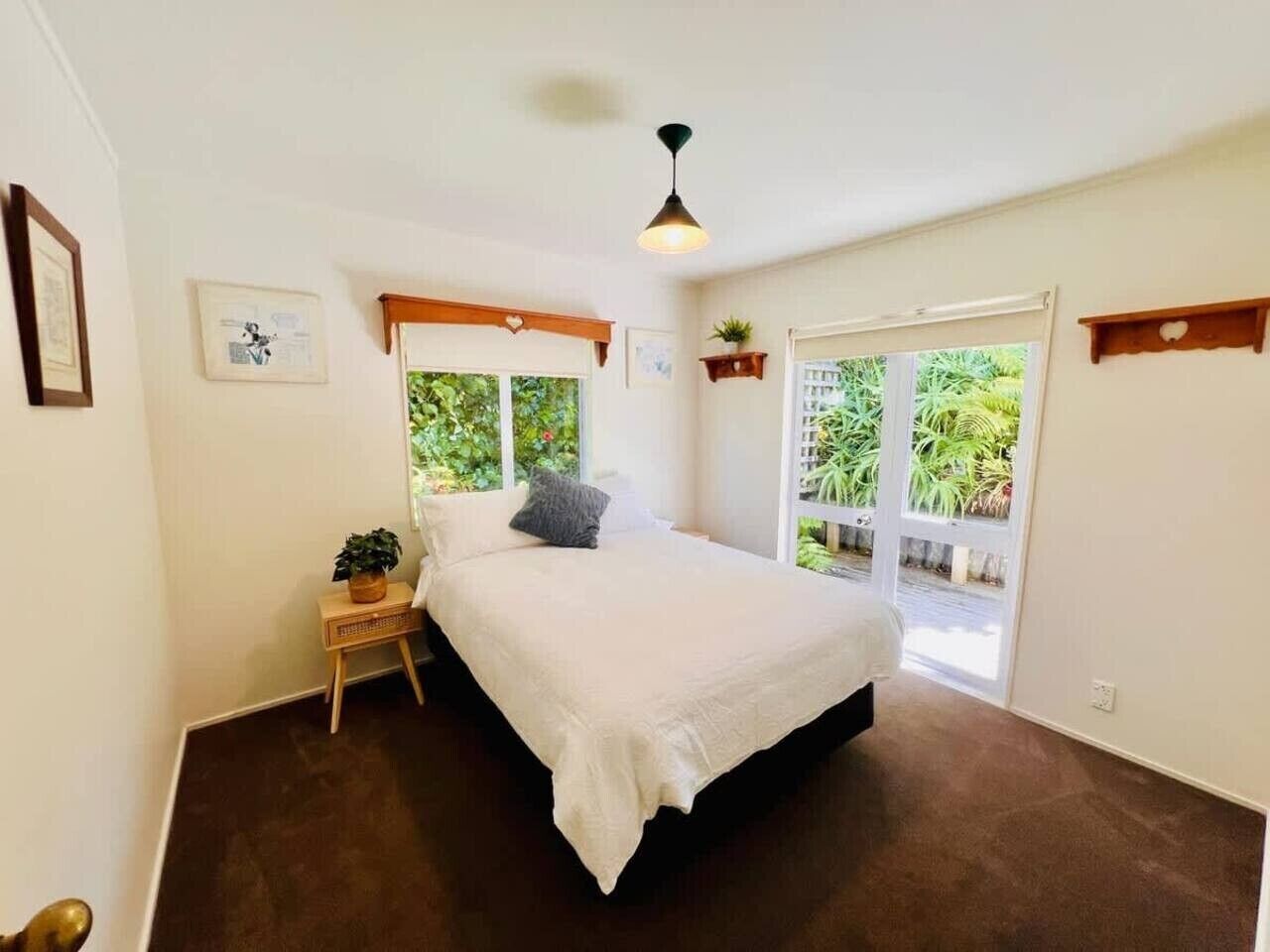 Een slaapkamer met een bed, nachtkastje en uitzicht op groen.