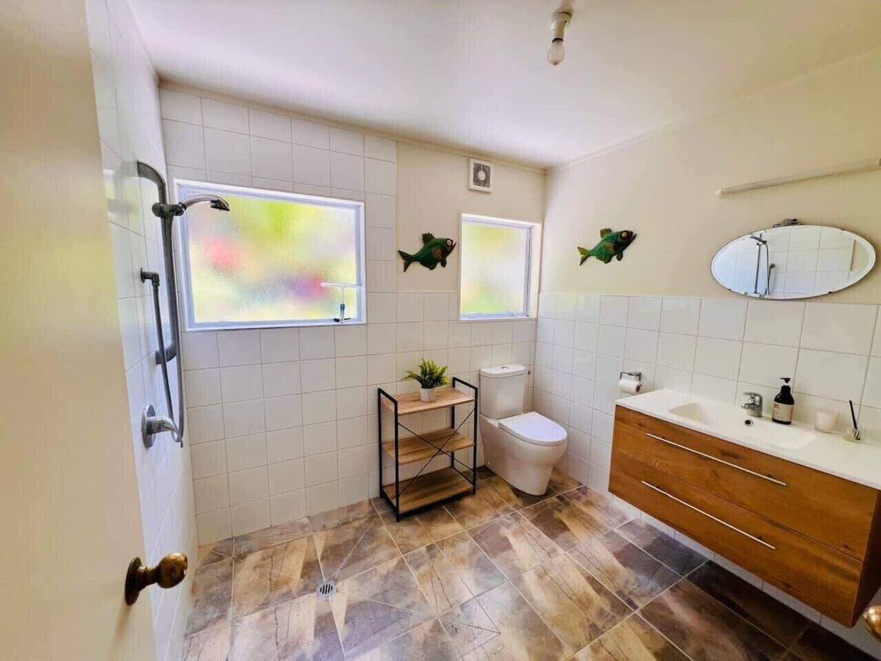 A bathroom with a toilet, sink, and a small shelf with a plant.