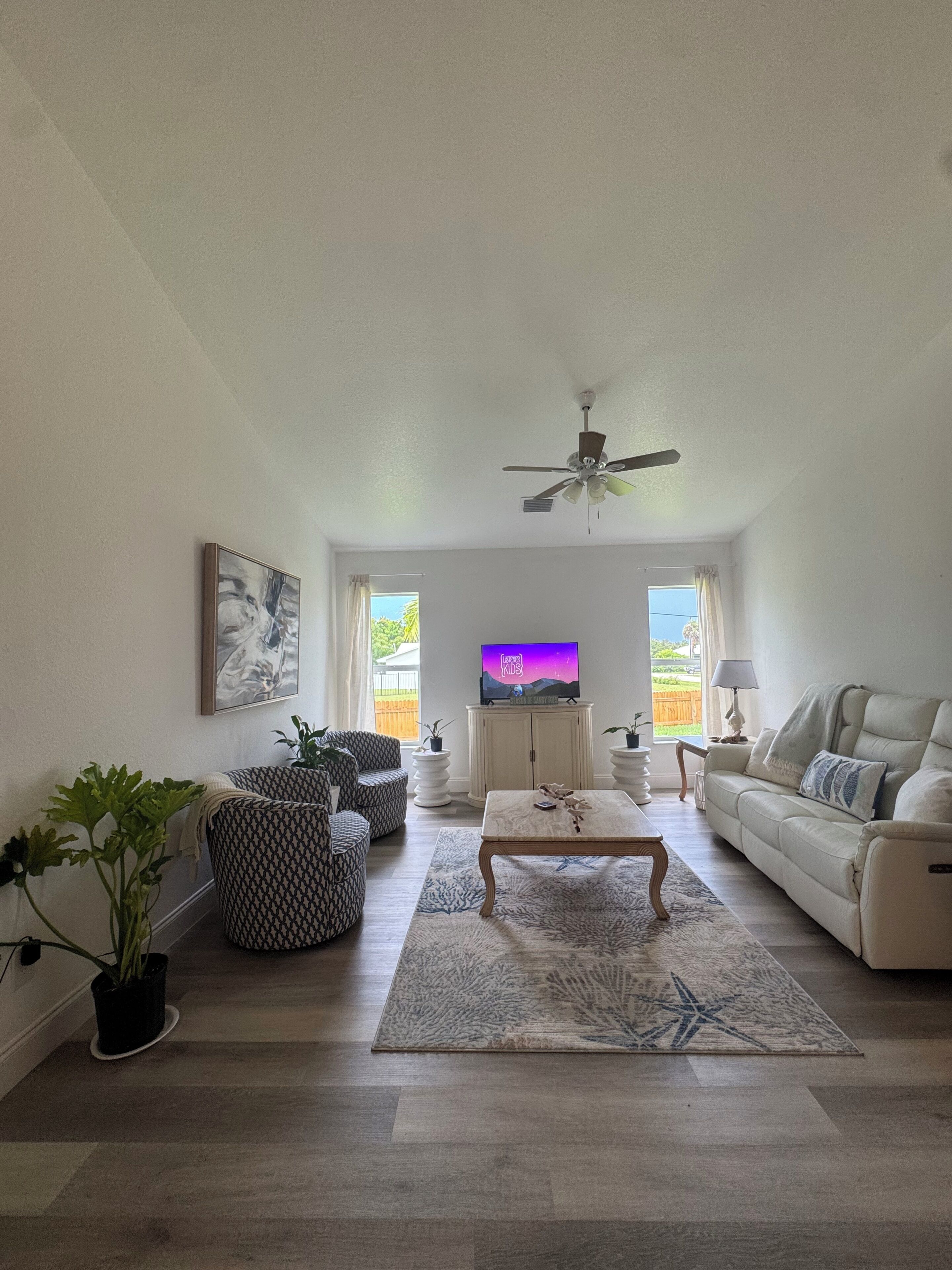 Ein Wohnzimmer mit Fernseher, Sofa, Couchtisch und gemusterten Stühlen.