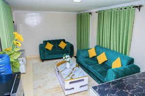 A living room with two sofas, a coffee table, and a decorative vase with flowers. - Luxury 2BR Apartment in Utawala  Free Wi-Fi  Near JKIA & SGR (Nairobi)
