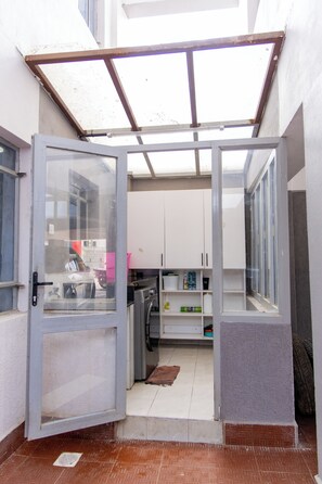 Um espaço exterior pequeno e fechado, com uma porta de vidro que dá para uma cozinha.