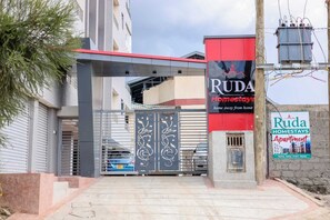 Uma entrada fechada para um complexo residencial, com uma placa indicando Ruda Homestays.