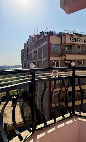 A building with a sign labeled 'GENESIS' and a balcony with a metal railing. - Cozy Homes Airbn. 15 minutes from JKIA in Kasarani, Nairobi (Nairobi)
