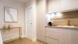Een moderne keuken met een houten visgraatvloer, een witte deur en een minimalistisch ontwerp.