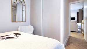 Een moderne slaapkamer met een groot bed, een spiegel en uitzicht op de woonkamer.