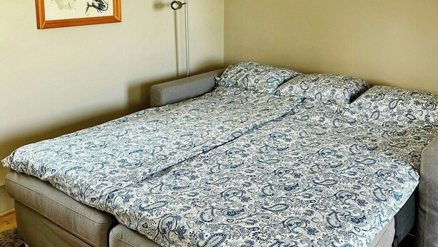 Una habitació amb un llit, una làmpada de peu i un quadre a la paret.
