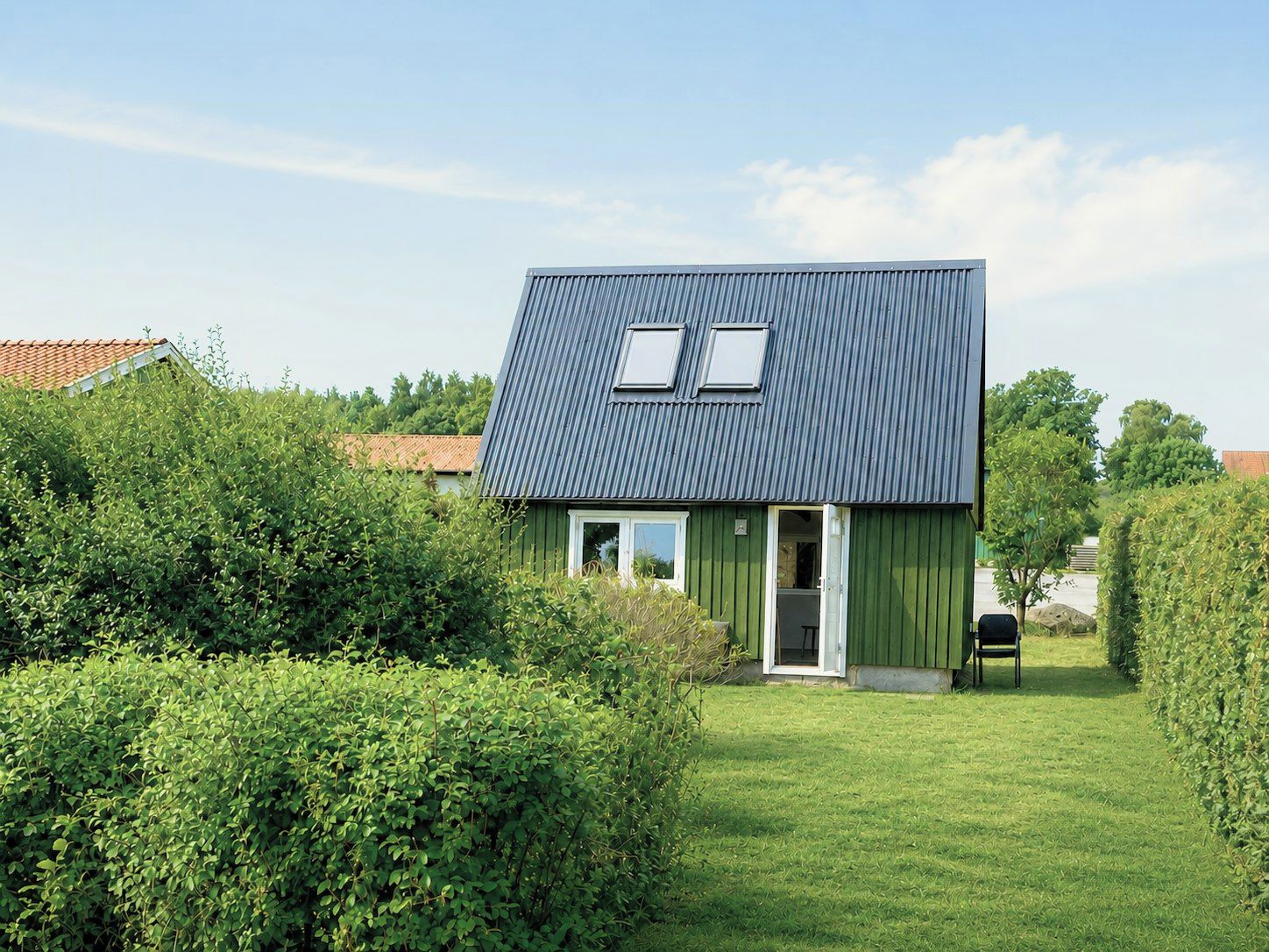 Ett modernt hus med ett sluttande tak, en liten veranda och en välskött gräsmatta.