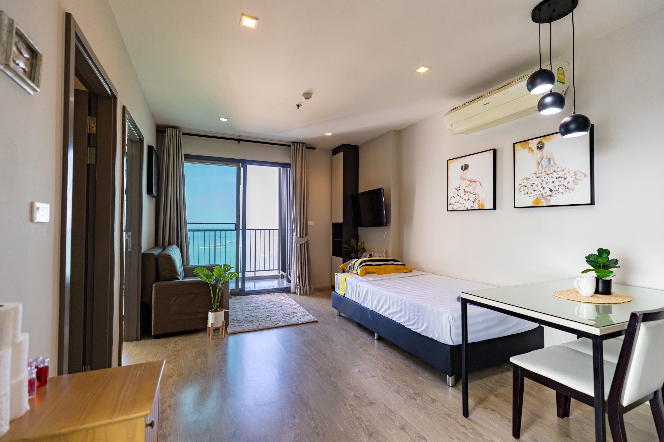 A modern hotel room with a balcony, a bed, a desk, and a chair.