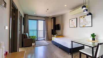 A modern hotel room with a balcony, a bed, a desk, and a chair.