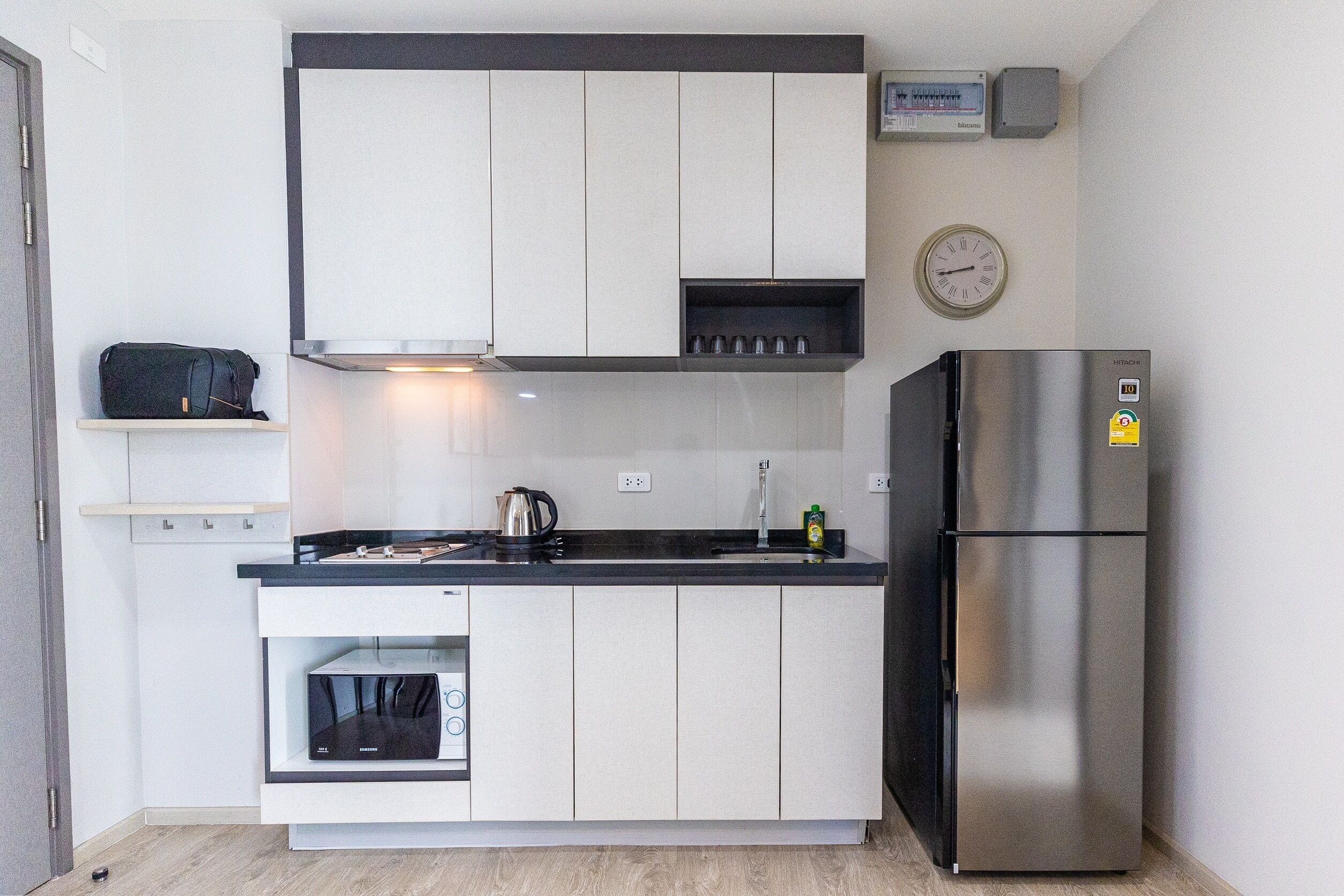 A compact kitchen with a built-in oven, a stainless steel refrigerator, and a microwave.
