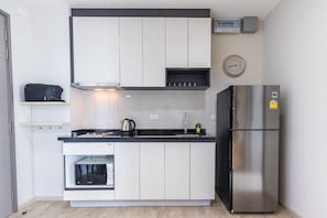 Una cocina compacta con horno integrado, refrigerador de acero inoxidable y microondas.