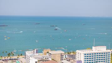 Un paysage urbain côtier avec un port de plaisance rempli de bateaux, des immeubles dotés de balcons donnant sur la mer et un hôtel appelé « The Bayview », qui offre une vue sur l’océan.