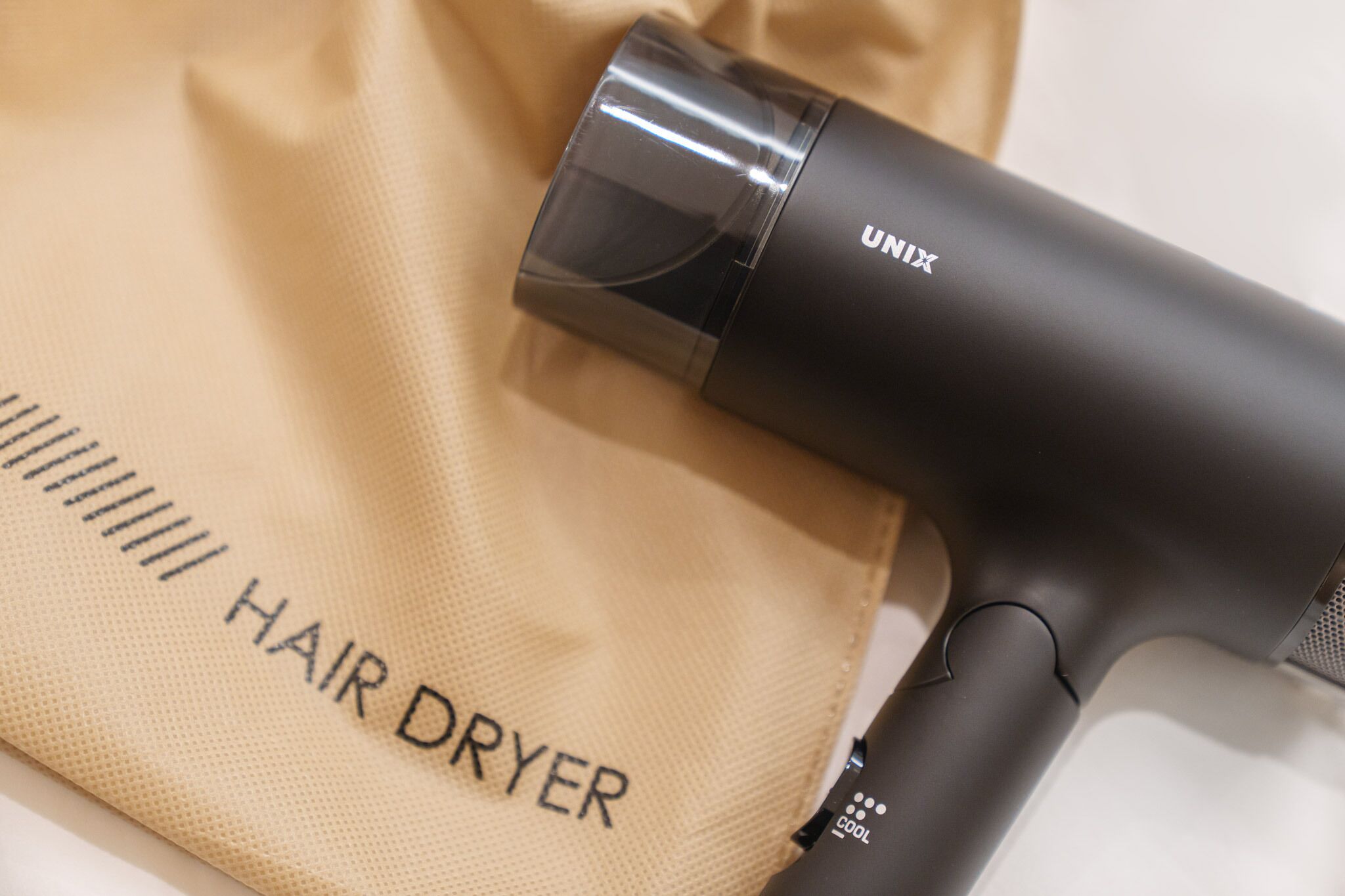 Een haardroger met het merk 'UNIX' en een beige doek waarop 'HAARDROGER' staat geschreven.