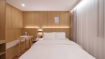 A hotel room with a bed, bedside table, lamp, and a phone.