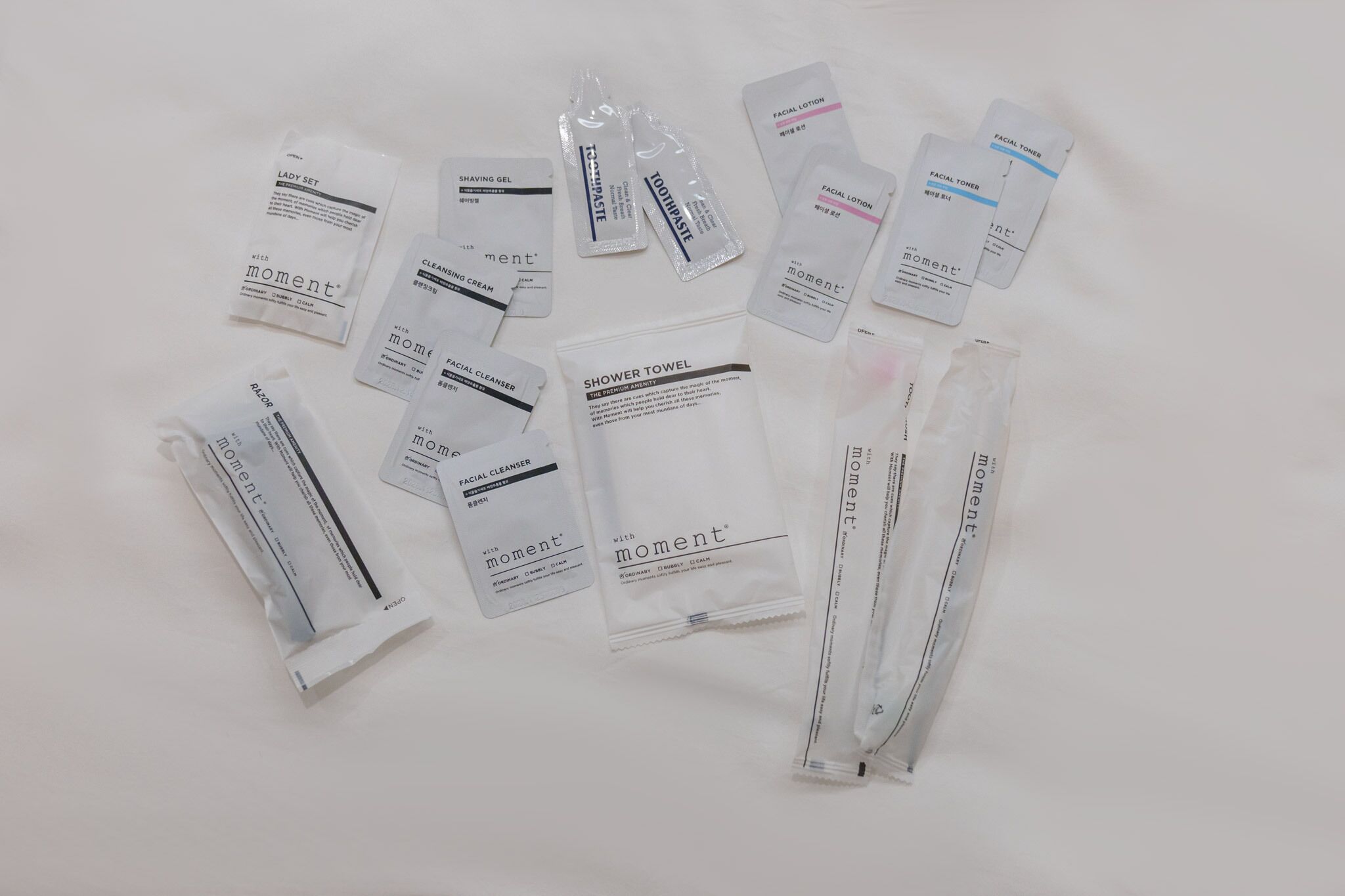A collection of personal care items including shaving gel, toothpaste, facial cleanser, facial toner, and a shower towel.