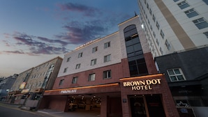 Un hotel con entrada a estacionamiento, varios pisos y un café visible.