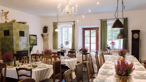 A dining area with multiple tables set for a meal, a chandelier, and a clock on the wall. - Holiday Homes with Sokolik Mountain Views (Janowice Wielkie)