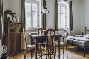 A room with a wooden table, chairs, a radiator, a bed, and a window with curtains. - Countryside Stay in Trzcinsko (Janowice Wielkie)