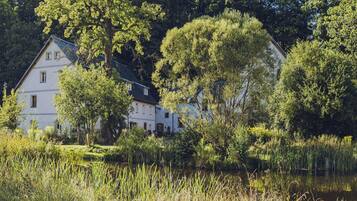 A two-story house with a garden and a pond.