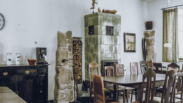 Ein Essbereich mit Holztisch und -stühlen, einer Steinwand und einem grünen Schrank mit Dekoration.