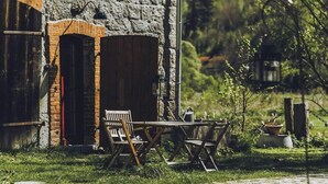 Un edificio rustico in pietra con un arco in mattoni, una panchina di legno e un tavolo all'aperto.