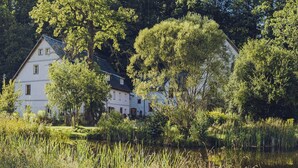 Una casa a due piani con un giardino e uno stagno.