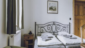 Una camera da letto con due letti, un comodino con una lampada, una porta in legno e un quadro appeso al muro.