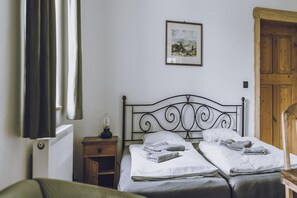 A bedroom with two beds, a nightstand with a lamp, a wooden door, and a framed picture on the wall. - 1-Bed Flat near Forest & River (Janowice Wielkie)
