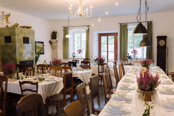 A dining area with multiple tables set for a meal, a chandelier, and a clock on the wall.
